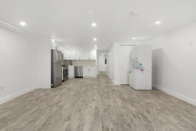 wyremontowane mieszkanie po stanie deweloperskim, sciany w kolorze białym i w tle już zamontowana kuchnia w kolorze białym.